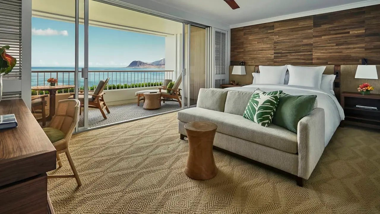 Four Seasons Resort Oahu at Ko Olina guestroom with a sofa, patterned carpet, a king bed and an ocean-view lanai; design reference photograph