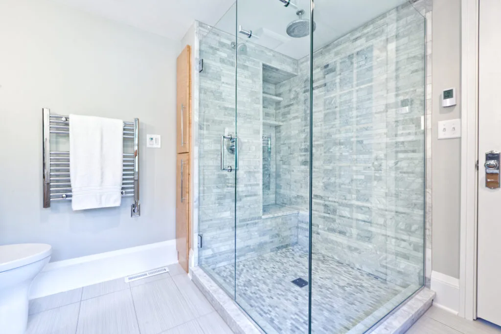 Before and after of professional hard water spot removal and glass restoration on a Waikiki hotel shower door