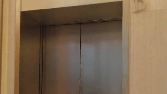 Technician performing commercial elevator scratch removal and metal panel refinishing in Honolulu
